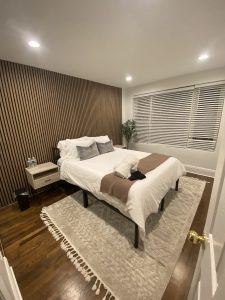 Wooden slat accent wall installation in modern bedroom by Flash Handy