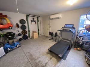 Garage gym setup with wall-mounted fitness equipment and treadmill by Flash Handy