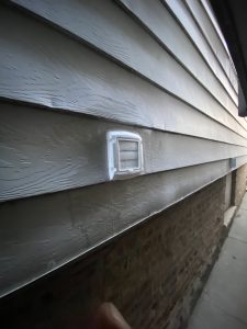 Installed white exterior wall vent on horizontal vinyl siding – Flash Handy handyman service